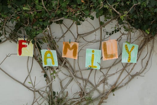 Word "FAMILY" painted on the paper A4 format and attached to the branches of the tree