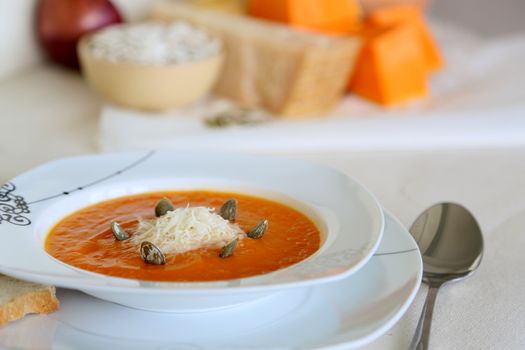 a plate of pumpkin cream soup prepared from onion,pumpkin,potatoes, pumpkin seed and parmesan cheese.