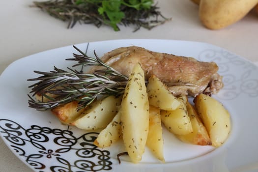 A plate of backed potatoes and chicken with rosemary
