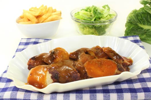 a currywurst with french fries and salad