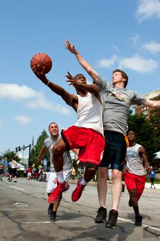 Athens, GA, USA - August 24, 2013:  A young man jumps to get off a shot against a defender, in a 3-on-3 basketball tournament held on the streets of downtown Athens.