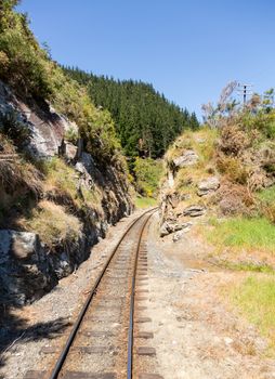 Railway track of Taieri Gorge tourist railway cuts through a narrow cutting in the rocks on its journey up the valley