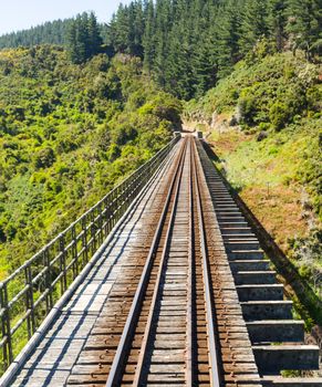 Railway track of Taieri Gorge tourist railway crosses a bridge across a ravine on its journey up the valley