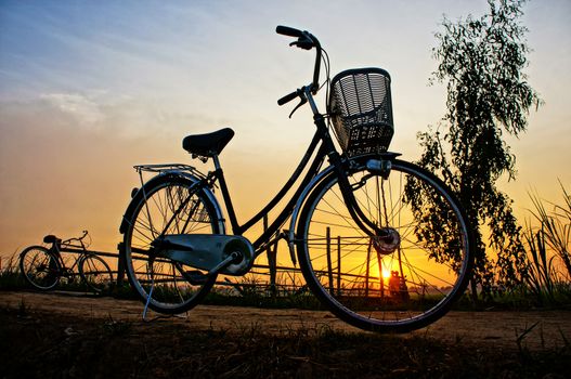 Beautiful landscape of nature with impression 's sun and silhouette of two bicycles in sunrise at countryside