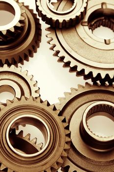 Metal cog gears bonding together on plain background