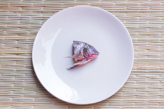 small fish's head in a big grey dish on a traditional mat