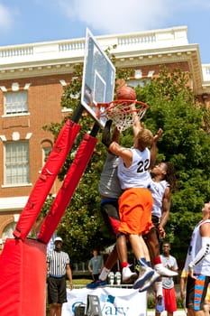 Athens, GA, USA - August 24, 2013:  Three men fight for the ball above the rim, in a 3-on-3 basketball tournament held on the streets of downtown Athens.