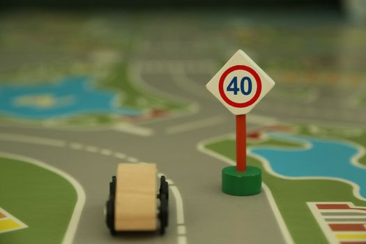 mini wooden road sign "speed limit 40" and mini wooden car - imitation of a typical situation on the street.
Abstract understanding of a message: "Respect the rules of the game, negociation, society where you live and do not allow yourself to violate them"