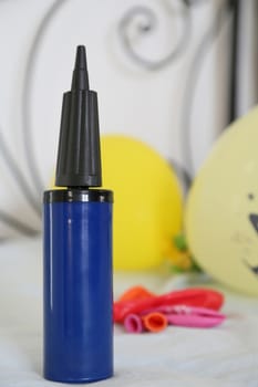 dark blue hand-held balloon inflator with colorful balloons in the background