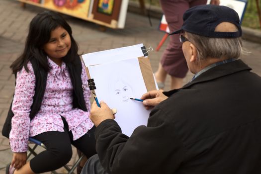 LIMA, PERU - SEPTEMBER 25, 2011: Unidentified street artist drawing a picture of an unidentified young Peruvian girl on September 25, 2011 in the district of Miraflores in Lima, Peru (Selective Focus, Focus on the drawing)