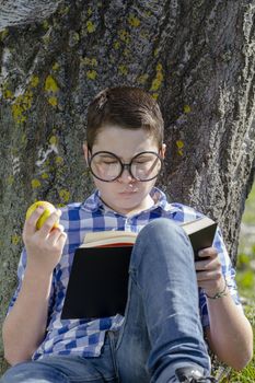 Young boy reading a book in the woods with shallow depth of field and copy space