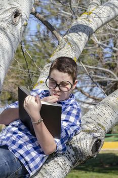 Young boy reading a book in the woods with shallow depth of field and copy space