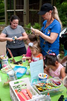 Roswell, GA, USA - July 13, 2013:  Parents help their children make art projecst at the arts and crafts table  at the Chattahoochee Nature Center's Butterfly Festival. Hundreds of people attended the two-day festival. 