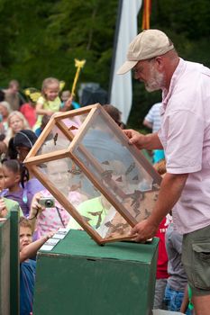 Roswell, GA, USA - July 13, 2013:  An unidentified man releases butterflies from a box, as the crowd looks on at the Chattahoochee Nature Center's Butterfly Festival. 