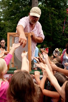 Roswell, GA, USA - July 13, 2013:  An unidentified man releases butterflies from a box, as a crowd of youthful hands reach for them at the Chattahoochee Nature Center's Butterfly Festival.