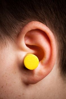 yellow earplug into the ear close up