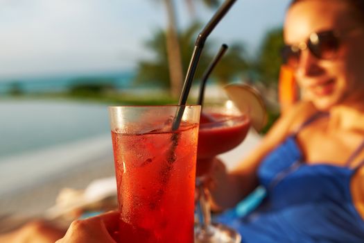 Couple clinking glasses with cocktails at poolside