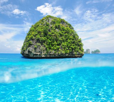 Beautiful uninhabited island in Thailand with white sand bottom underwater and above water split view