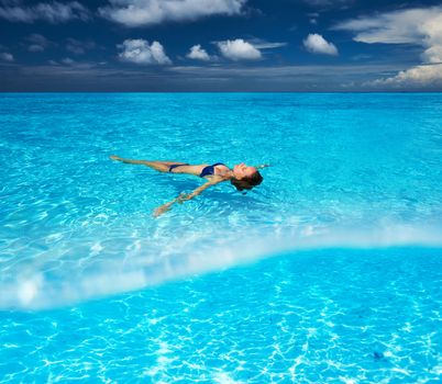 Woman in bikini lying on water at tropical beach