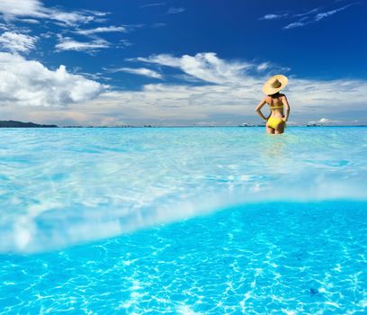 Girl on a tropical beach with white sand bottom underwater and above water split view