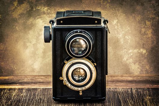 Old fashioned antique camera in vintage style with filtered textured background