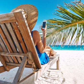 Young woman in hat with mobile phone at the beach