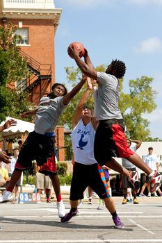 Athens, GA, USA - August 24, 2013:  Three young men fight for a rebound while playing in a 3-on-3 basketball tournament held on the streets of downtown Athens.
