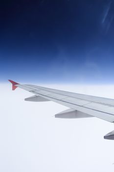 Wing of an airplane flying above the clouds. people looks at the sky