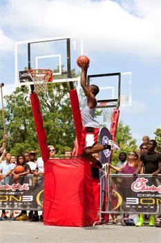 Athens, GA, USA - August 24, 2013:  A young man elevates above the rim to dunk a basketball in the slam dunk competition of a 3-on-3 basketball tournament held in the streets of downtown Athens.