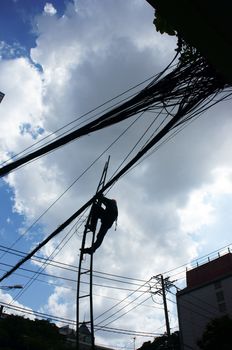 Electrician working among electric wire network in the blue sky as spider