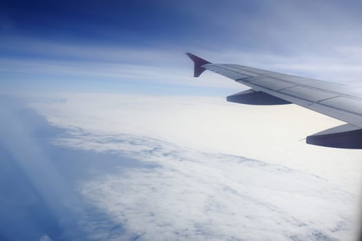 Wing of an airplane flying above the clouds. people looks at the sky