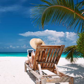 Young woman in hat with tablet pc at the beach