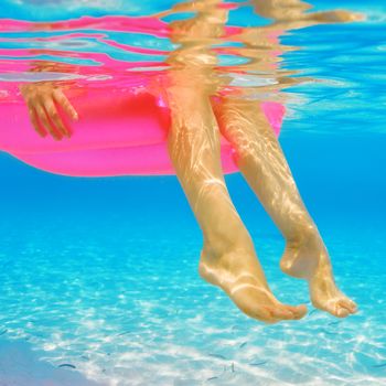 Woman relaxing on inflatable mattress at the beach, view from underwater