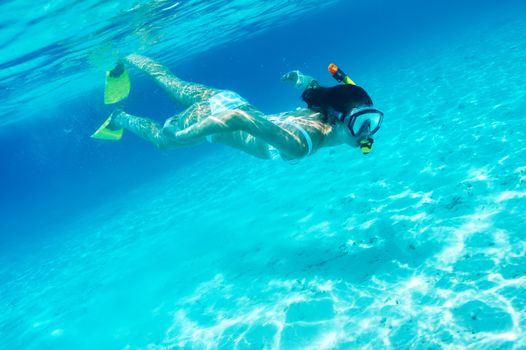 Woman with mask snorkeling in clear water 