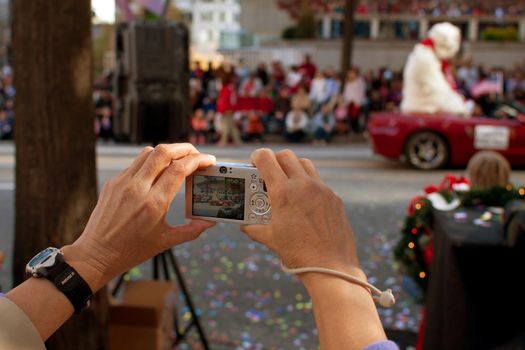 Atlanta, GA, USA - December 1, 2012:   A woman's hands hold a point and shoot camera as she captures moments from the annual Atlanta Christmas parade in downtown Atlanta.
