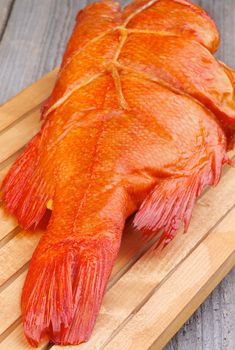 Delicious Smoked Red Snapper Fish Full Body on Cutting Board closeup on Wooden background