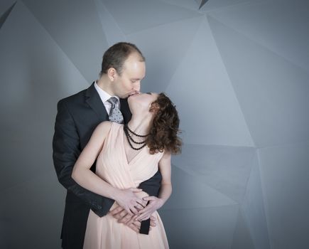 young man gently embraces a girl on a grey background