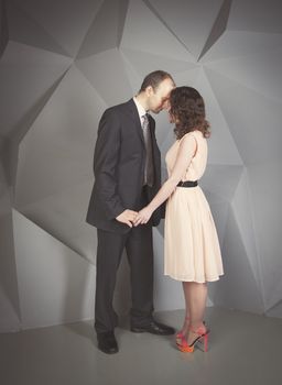 young man gently embraces a girl on a grey background