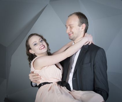 young man gently embraces a girl on a grey background