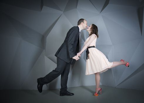 young man gently embraces a girl on a grey background