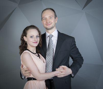 young man gently embraces a girl on a grey background