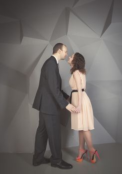 young man gently embraces a girl on a grey background