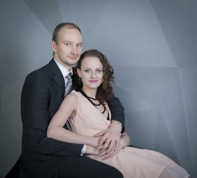 young man gently embraces a girl on a grey background