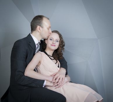 young man gently embraces a girl on a grey background