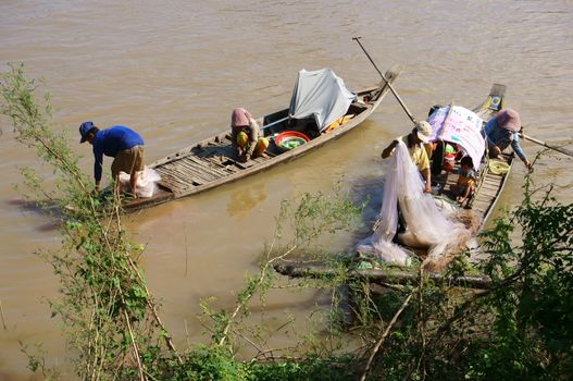 HONG NGU, VIET NAM- NOV 12: Families of fisherman do fishing on river, on the row boat, husban cast a net, his wife do fish in clean, children play alone in Hong Ngu, Viet Nam on Nov 12, 2013