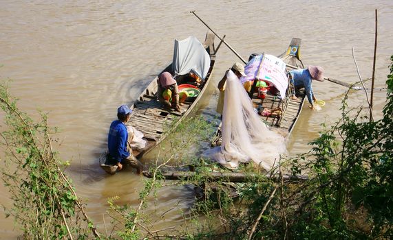 HONG NGU, VIET NAM- NOV 12: Families of fisherman do fishing on river, on the row boat, husban cast a net, his wife do fish in clean, children play alone in Hong Ngu, Viet Nam on Nov 12, 2013