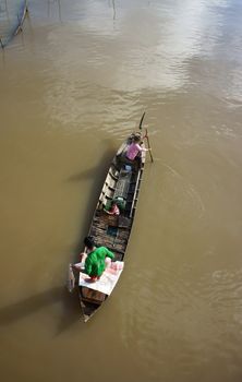 rowing the wooden boat, the man cast a net ro catch fish, children sitting on the boat in Dong Thap, Viet Nam on Nov 12, 2013