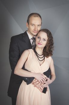 young man gently embraces a girl on a grey background