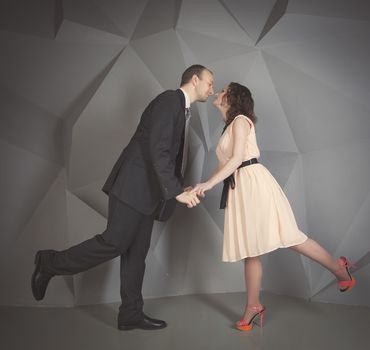 young man gently embraces a girl on a grey background