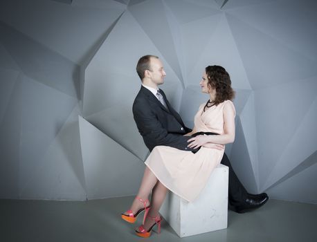 young man gently embraces a girl on a grey background